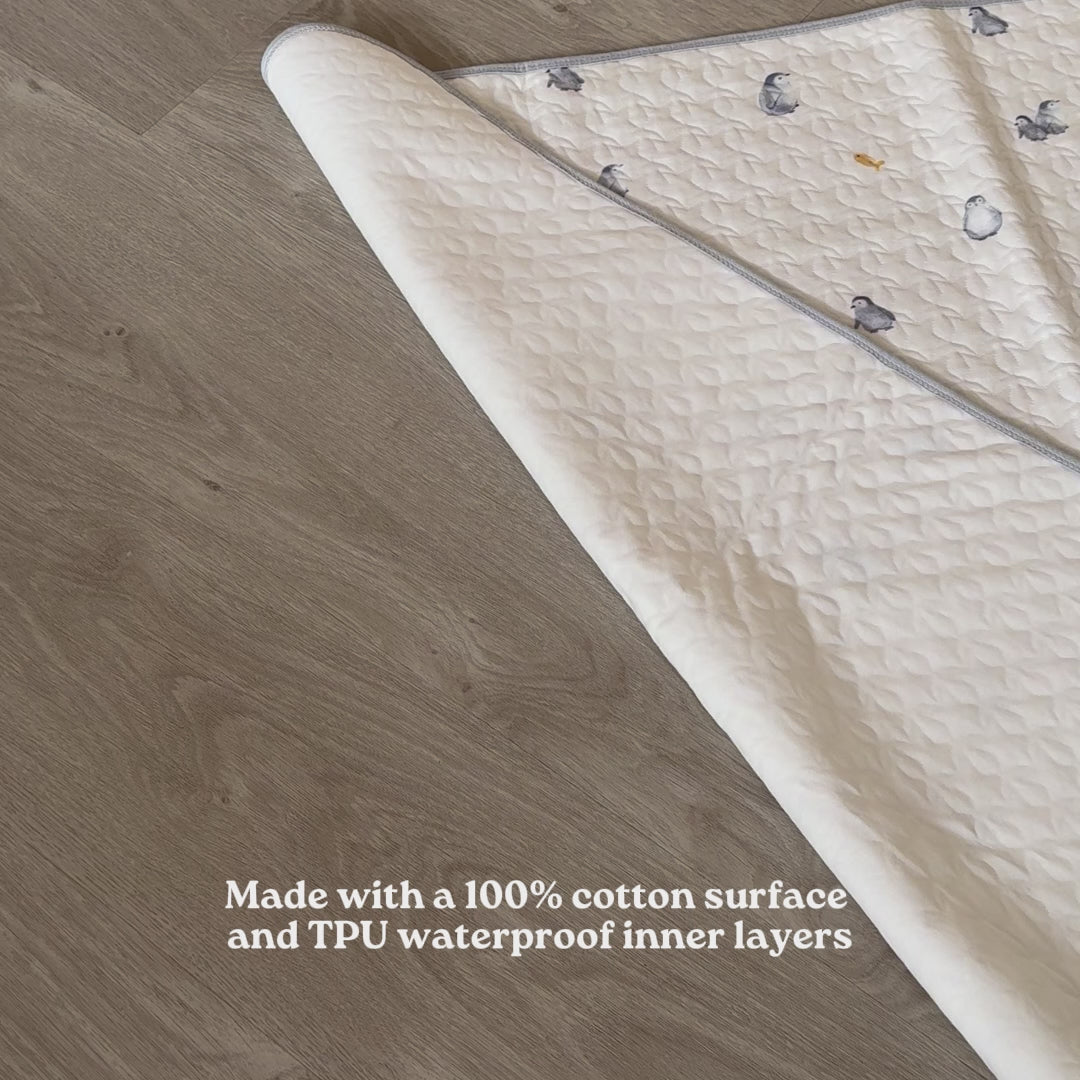 2-in-1 Diaper Mat and Mattress Protector laying flat on a table, person adding a tissue paper underneath the mattress protector and continue pouring water on the mattress protector showing how absorbent cotton the material and the water does not spill on the bottom side of the mattress protector because of it's TPU membrane inner layer, person continues to  show that the tissue placed underneath is still dry